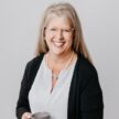 Betsie Hughes smiling, holding a coffee mug, professional portrait for Preferred Rate.