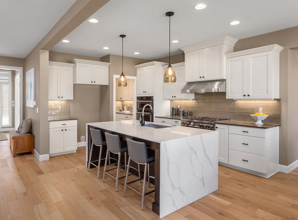 Modern kitchen with white cabinetry, island, and stainless steel appliances for home renovation fina.
