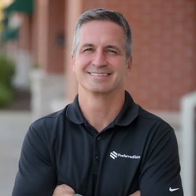 Confident man in black polo shirt with Preferred Rate logo outdoors.