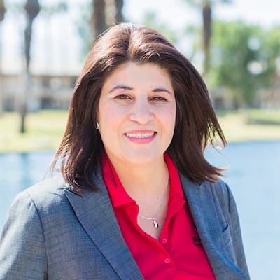 Businesswoman smiling outdoors with a professional look for financial services.