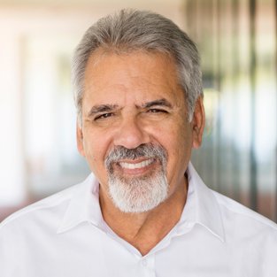 George Muñoz smiling in a professional setting at Preferred Rate.