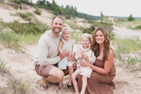 Family enjoying outdoor time on sandy dunes, promoting financial stability and family planning servi.