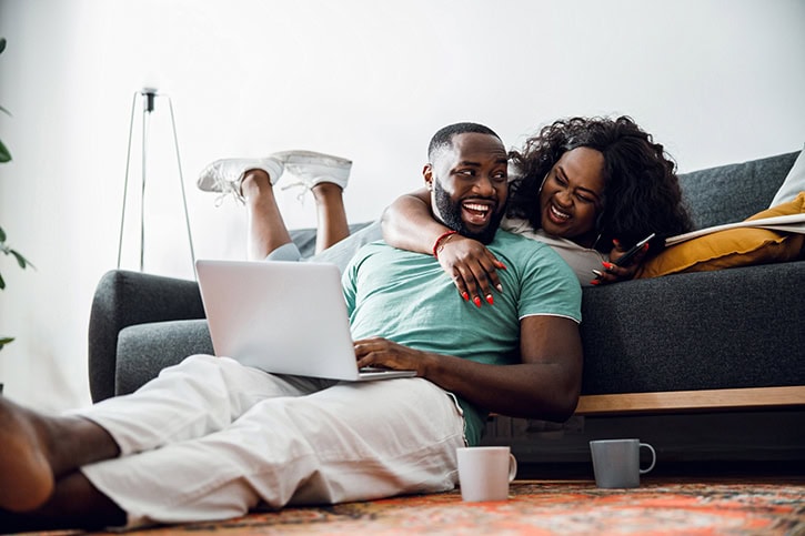 Happy couple using a laptop on the floor, discussing home equity line of credit options.