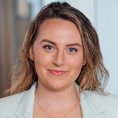 Professional portrait of Elise Elizalde, smiling woman with blue eyes and wavy hair.