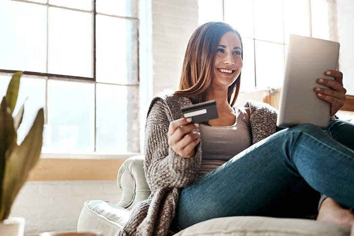 Woman using laptop and credit card, learning about credit score calculation.