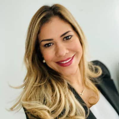 Professional woman smiling, blonde hair, business attire, confident and approachable.