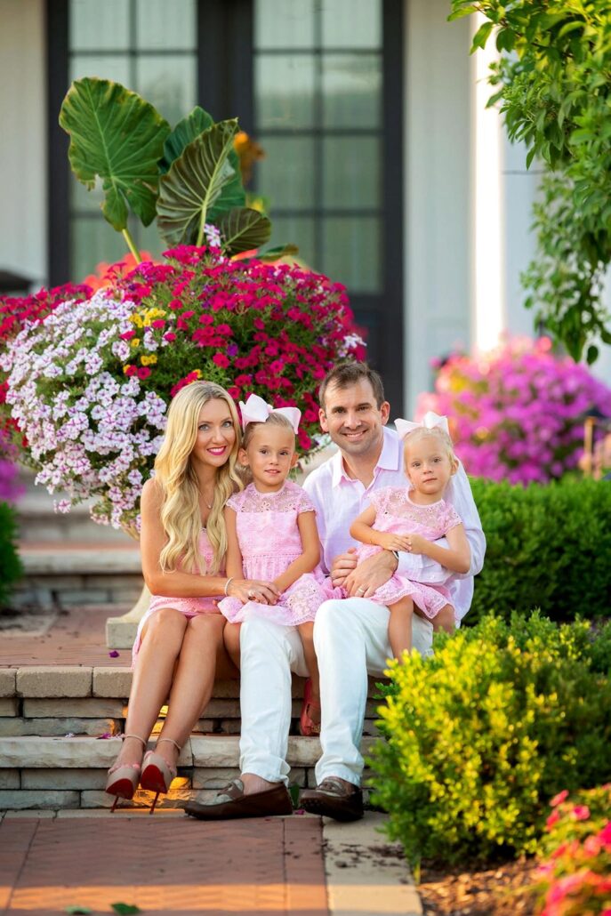 Family enjoying a sunny day on the porch with vibrant flowers.