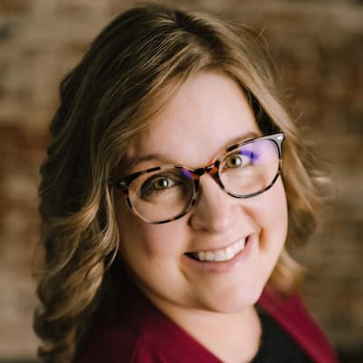 Portrait of Shantel Cartwright smiling, wearing glasses, in a professional setting.