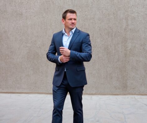 Business professional in navy suit standing outdoors for Mark Mayfield.
