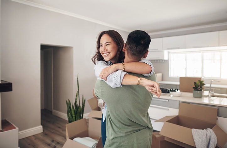 Happy couple embracing in new home after qualifying for first-time home buyer programs.