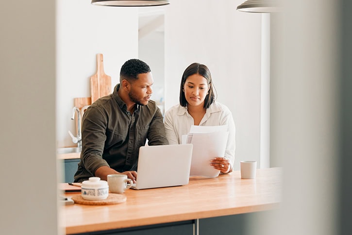 Couple reviewing credit documents and laptop for credit score improvement.