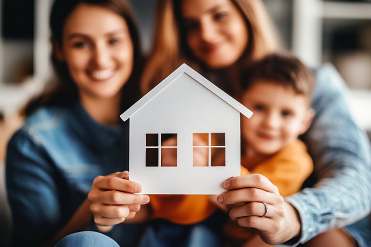Family holding a paper house model for homeownership budgeting.