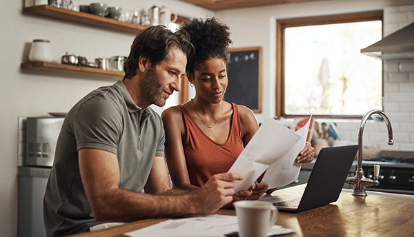 Couple reviewing documents for bridge loan in kitchen setting.