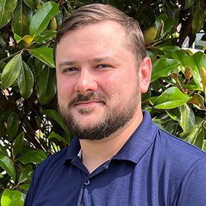 Christian Beck smiling outdoors with greenery in the background, representing trusted mortgage servi.