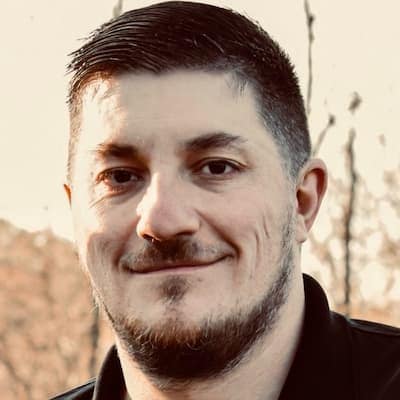 Portrait of Jason VanDermark, smiling outdoors during sunset.