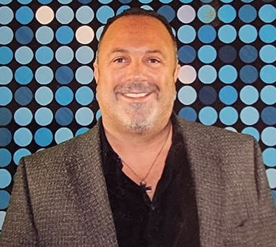 Philip Blaze smiling at Preferred Rate event with colorful dot background.