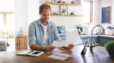 Happy, man and documents with tablet at house for financial planning, bank balance and debt payment. Male person, smile and paperwork for budget savings, property insurance and credit score growth