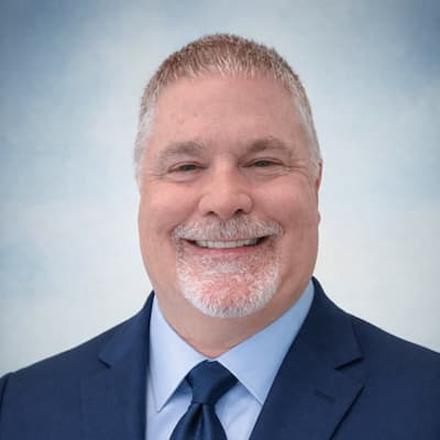 Kevin Jon Schudel smiling in a professional suit for Preferred Rate.